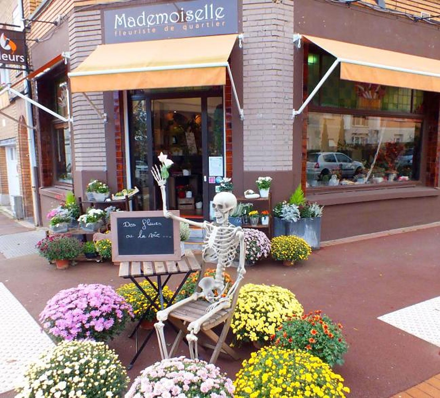 Devanture de la boutique avec un squelette décoratif et des chrysanthèmes sur le trottoir